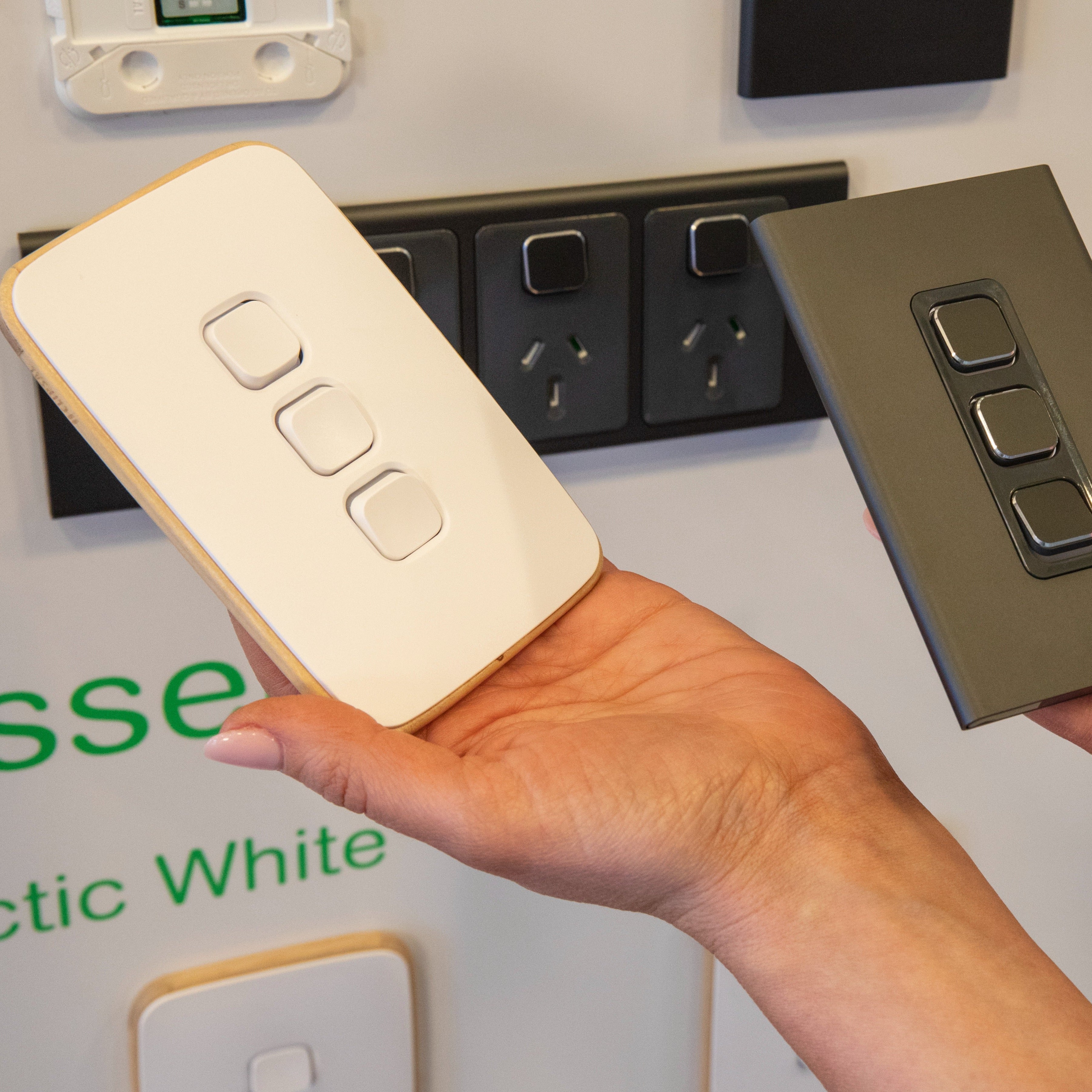 Hand holding a beige light switch cover next to a black switch, with 'Essex' branding in the background.