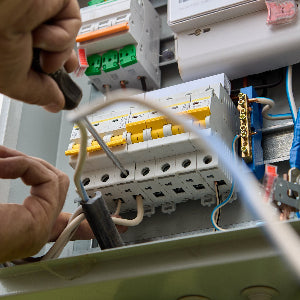 Person working with electrical wiring and a switchboard.